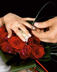 hands-over-wedding-bouquet-with-rings-on-black-background-studio-shot